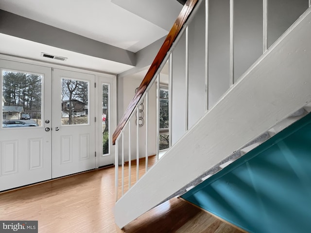 foyer featuring light wood-type flooring, visible vents, and stairway