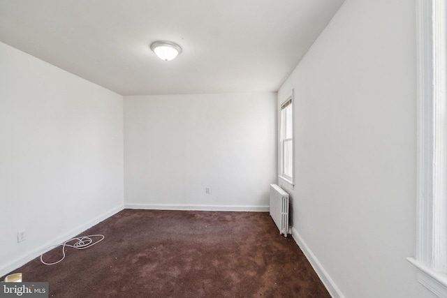 empty room featuring carpet, baseboards, and radiator heating unit