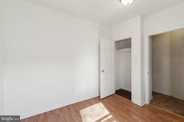 unfurnished bedroom with a closet, wood finished floors, and baseboards