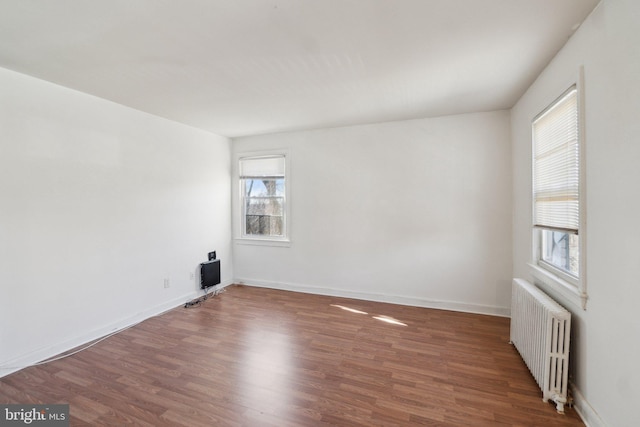 empty room with radiator, baseboards, and wood finished floors