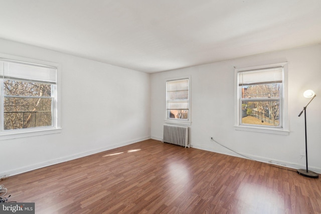 unfurnished bedroom featuring baseboards, wood finished floors, and radiator