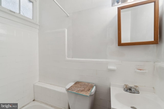 full bathroom featuring wainscoting, a sink, tile walls, and bathing tub / shower combination