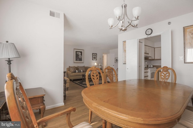 dining space with a chandelier, baseboards, visible vents, and light wood finished floors