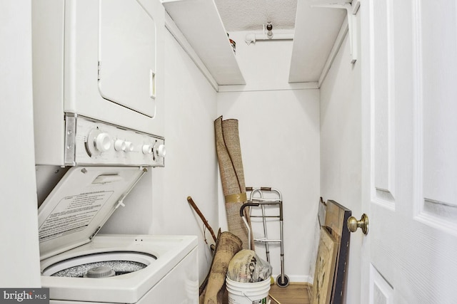 laundry area with laundry area, stacked washing maching and dryer, and wood finished floors