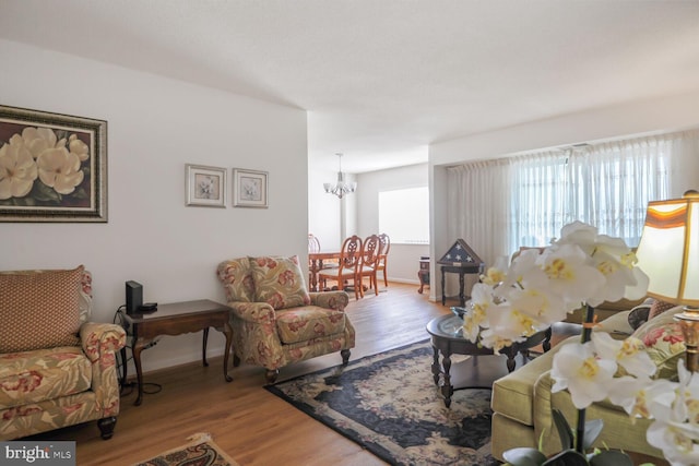 living area with baseboards, wood finished floors, and an inviting chandelier