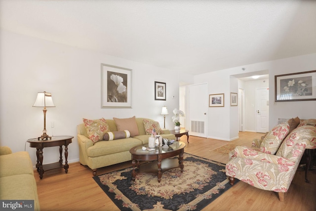 living room featuring visible vents, baseboards, and wood finished floors