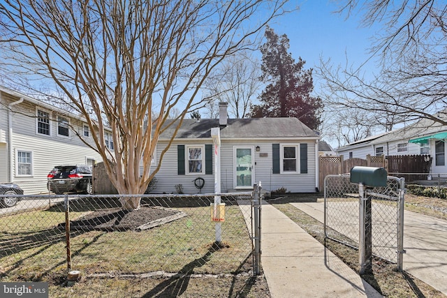 view of front of house featuring driveway, a fenced front yard, a chimney, and a gate