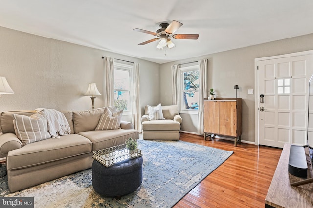 living area with baseboards, a ceiling fan, and wood finished floors