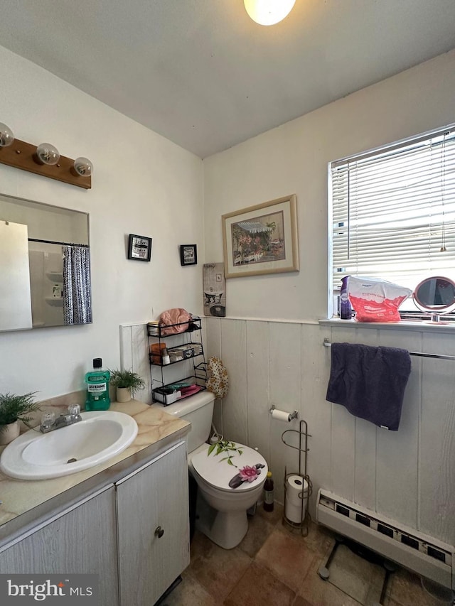 bathroom featuring walk in shower, vanity, toilet, and a baseboard heating unit