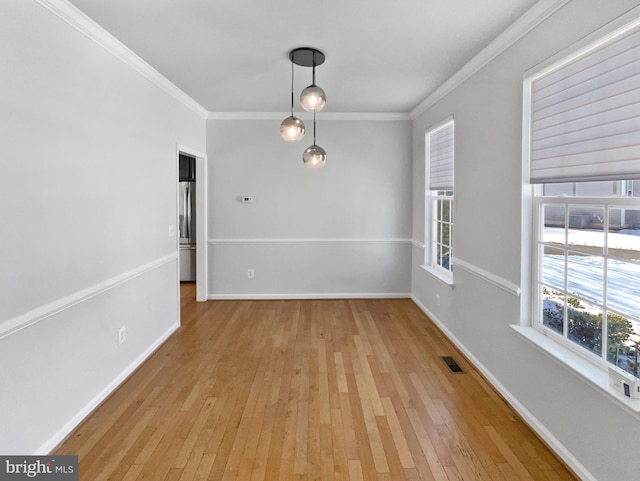 unfurnished dining area with ornamental molding and light hardwood / wood-style floors