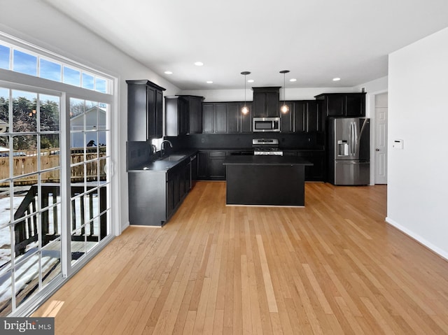 kitchen featuring a kitchen island, appliances with stainless steel finishes, pendant lighting, sink, and decorative backsplash