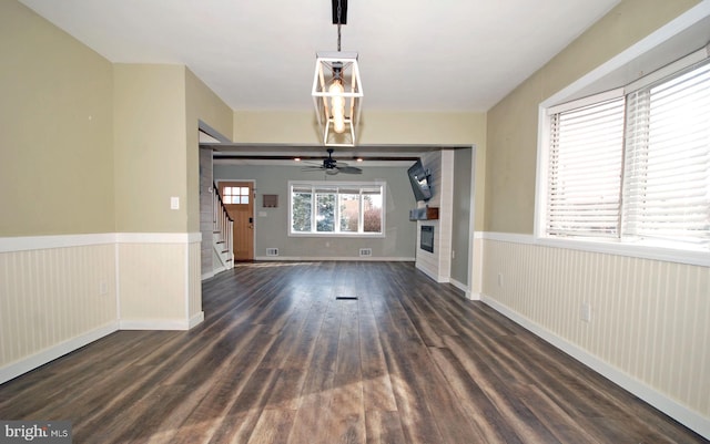 interior space with dark wood-style floors, stairway, wainscoting, and a glass covered fireplace