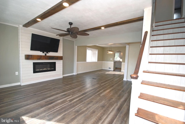 unfurnished living room featuring a large fireplace, stairway, dark wood finished floors, and beam ceiling