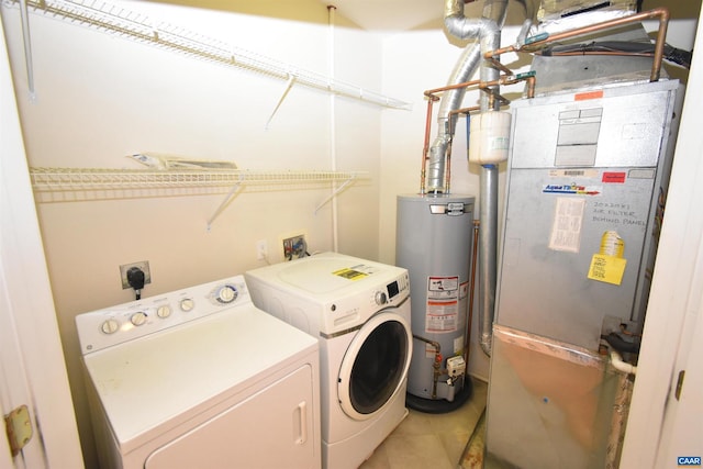 laundry area with tile patterned flooring, gas water heater, heating unit, and washer and clothes dryer