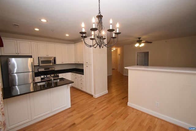 kitchen featuring white cabinetry, decorative light fixtures, appliances with stainless steel finishes, ceiling fan, and light hardwood / wood-style floors