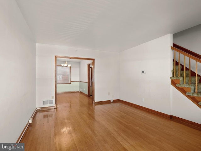 empty room with hardwood / wood-style flooring and a chandelier