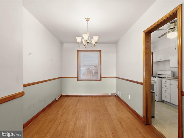 unfurnished dining area featuring light wood-type flooring and ceiling fan with notable chandelier