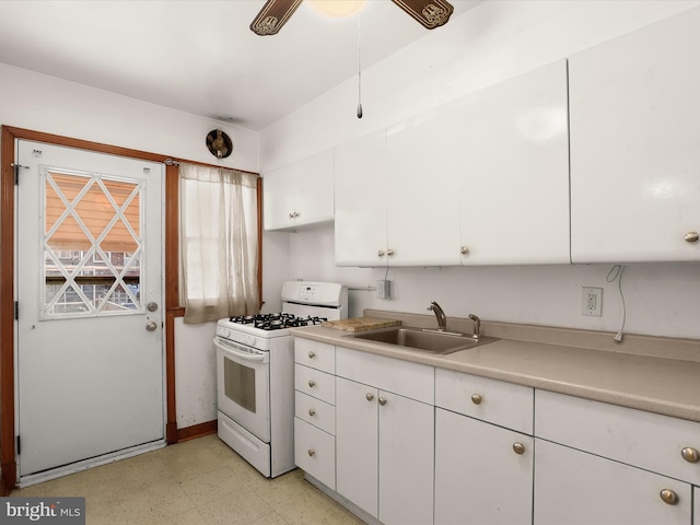 kitchen featuring sink, gas range gas stove, white cabinets, and ceiling fan