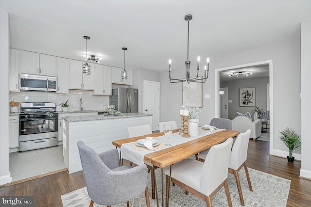 dining room with sink, an inviting chandelier, and dark hardwood / wood-style flooring