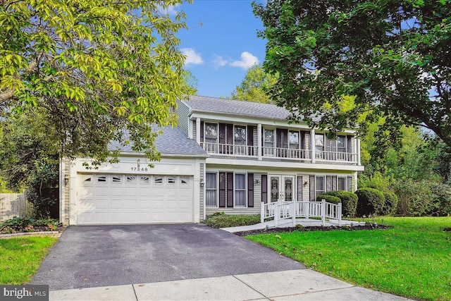 view of front of house featuring a balcony, a garage, and a front lawn