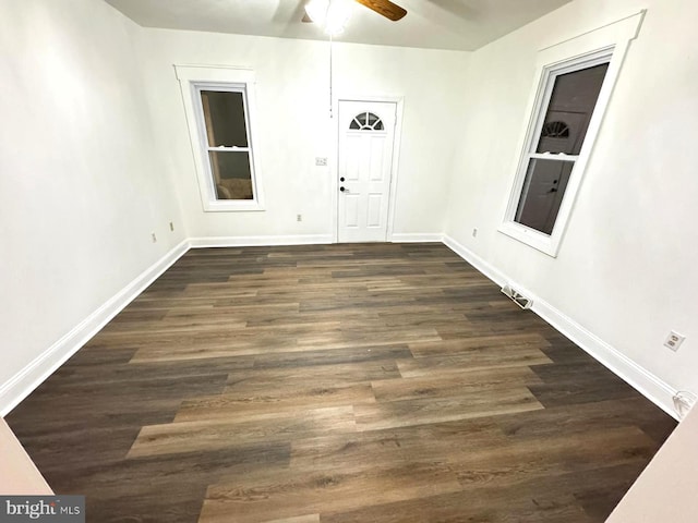 spare room with ceiling fan, baseboards, and dark wood-style floors