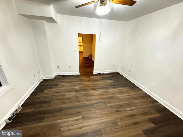 empty room featuring baseboards, a ceiling fan, and dark wood-style flooring