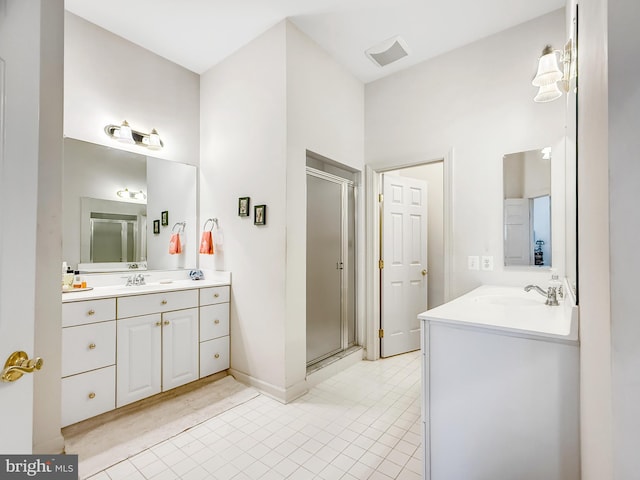 bathroom featuring a stall shower, two vanities, and a sink