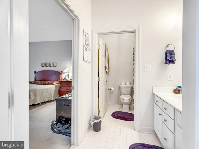 bathroom featuring toilet, connected bathroom, vanity, tile patterned flooring, and baseboards