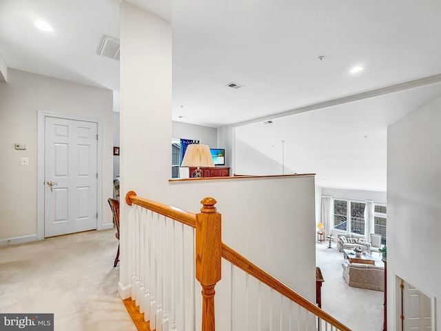 hall with recessed lighting, light carpet, visible vents, baseboards, and an upstairs landing