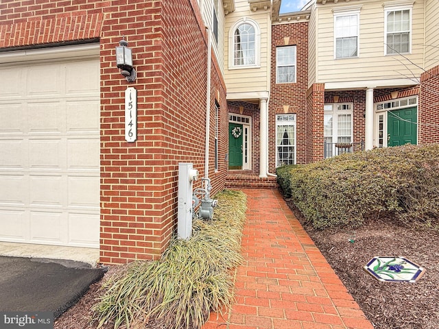 doorway to property featuring a garage and brick siding