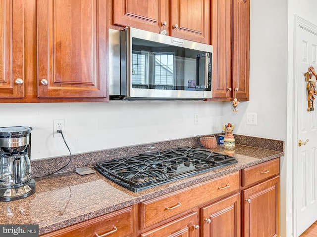 kitchen with black gas cooktop, brown cabinets, and stainless steel microwave