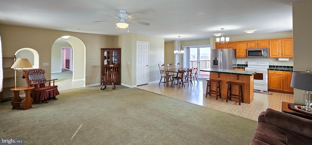 kitchen with stainless steel appliances, dark countertops, open floor plan, a kitchen island, and a kitchen breakfast bar