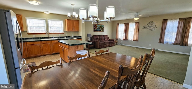 dining space with baseboards, a ceiling fan, and light colored carpet