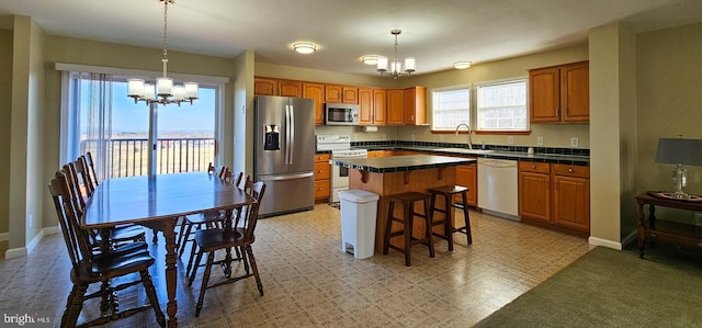 kitchen featuring hanging light fixtures, appliances with stainless steel finishes, dark countertops, and an inviting chandelier