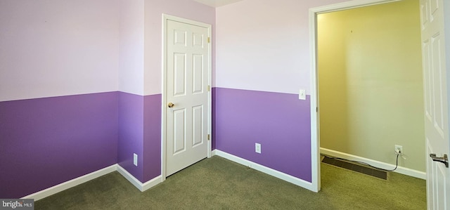 interior space featuring baseboards and dark colored carpet