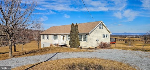 view of front of house featuring driveway, a mountain view, and a front yard