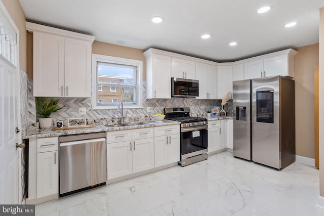 kitchen with light stone counters, a sink, stainless steel appliances, white cabinets, and marble finish floor