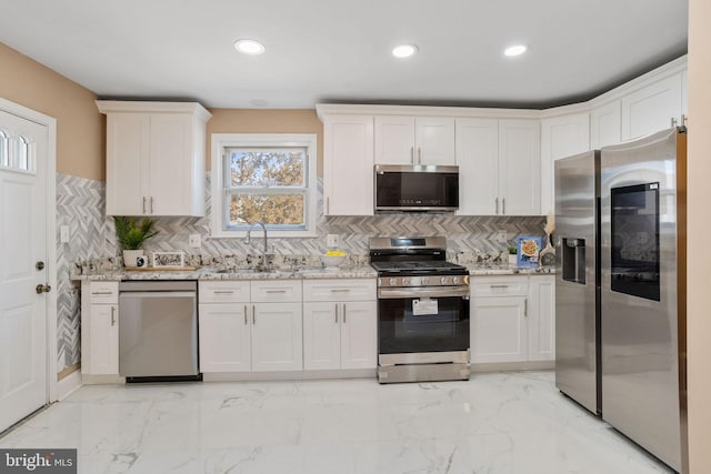 kitchen featuring light stone counters, marble finish floor, stainless steel appliances, and a sink