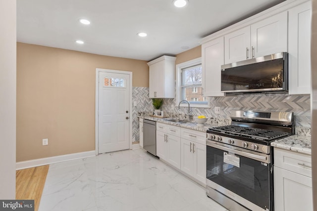 kitchen featuring tasteful backsplash, baseboards, marble finish floor, stainless steel appliances, and a sink