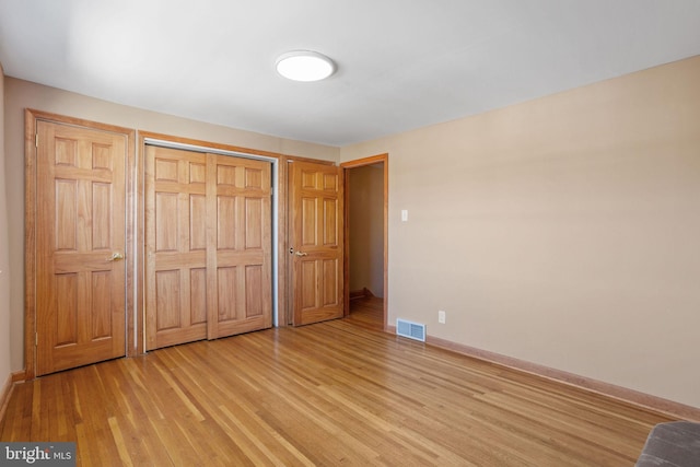 unfurnished bedroom featuring baseboards, visible vents, a closet, and light wood-type flooring