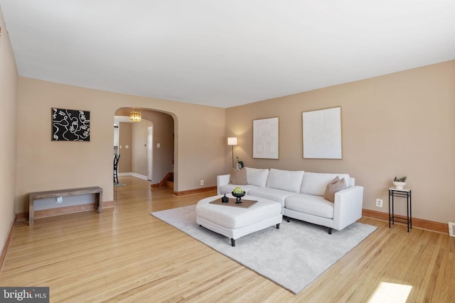 living area featuring baseboards, arched walkways, and wood finished floors