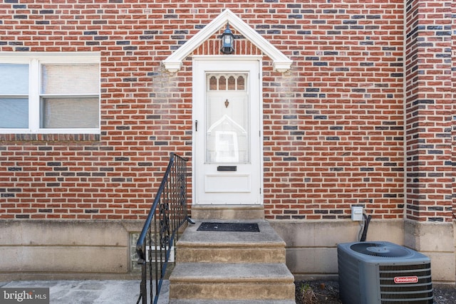 view of exterior entry with cooling unit and brick siding