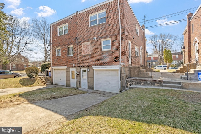 rear view of property with a yard, brick siding, concrete driveway, and an attached garage