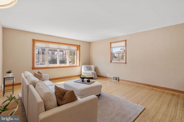 living area with visible vents, baseboards, and wood finished floors