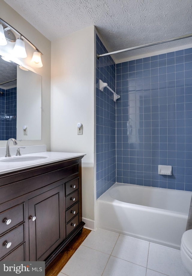 full bathroom with vanity, a textured ceiling, tiled shower / bath, tile patterned flooring, and toilet