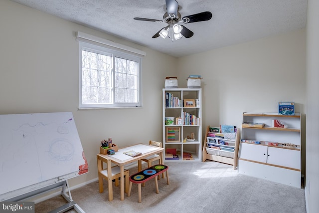 playroom featuring a textured ceiling, light colored carpet, and ceiling fan