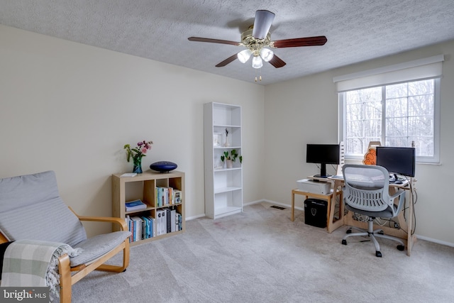 carpeted office space with a textured ceiling and ceiling fan