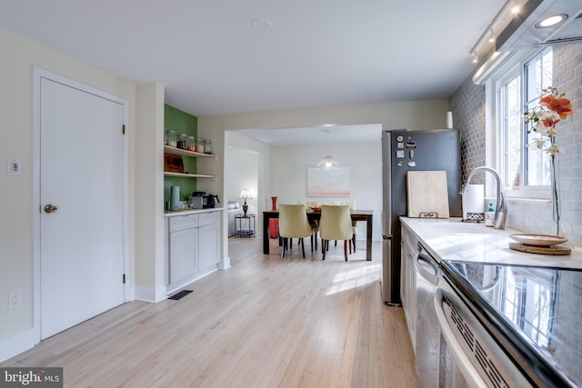 kitchen with light hardwood / wood-style flooring, sink, appliances with stainless steel finishes, white cabinets, and decorative backsplash