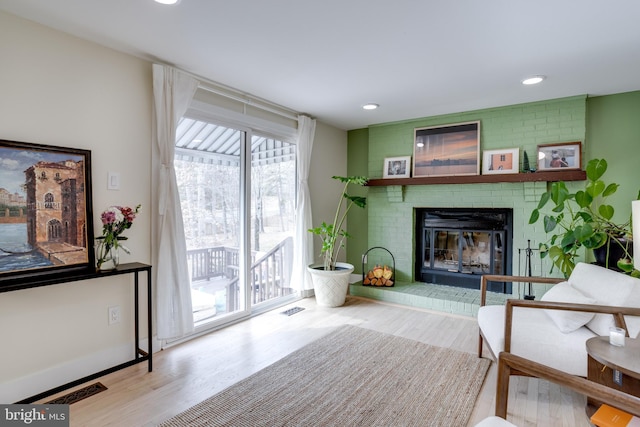 sitting room with a brick fireplace and hardwood / wood-style floors