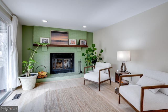 living area featuring hardwood / wood-style flooring and a brick fireplace